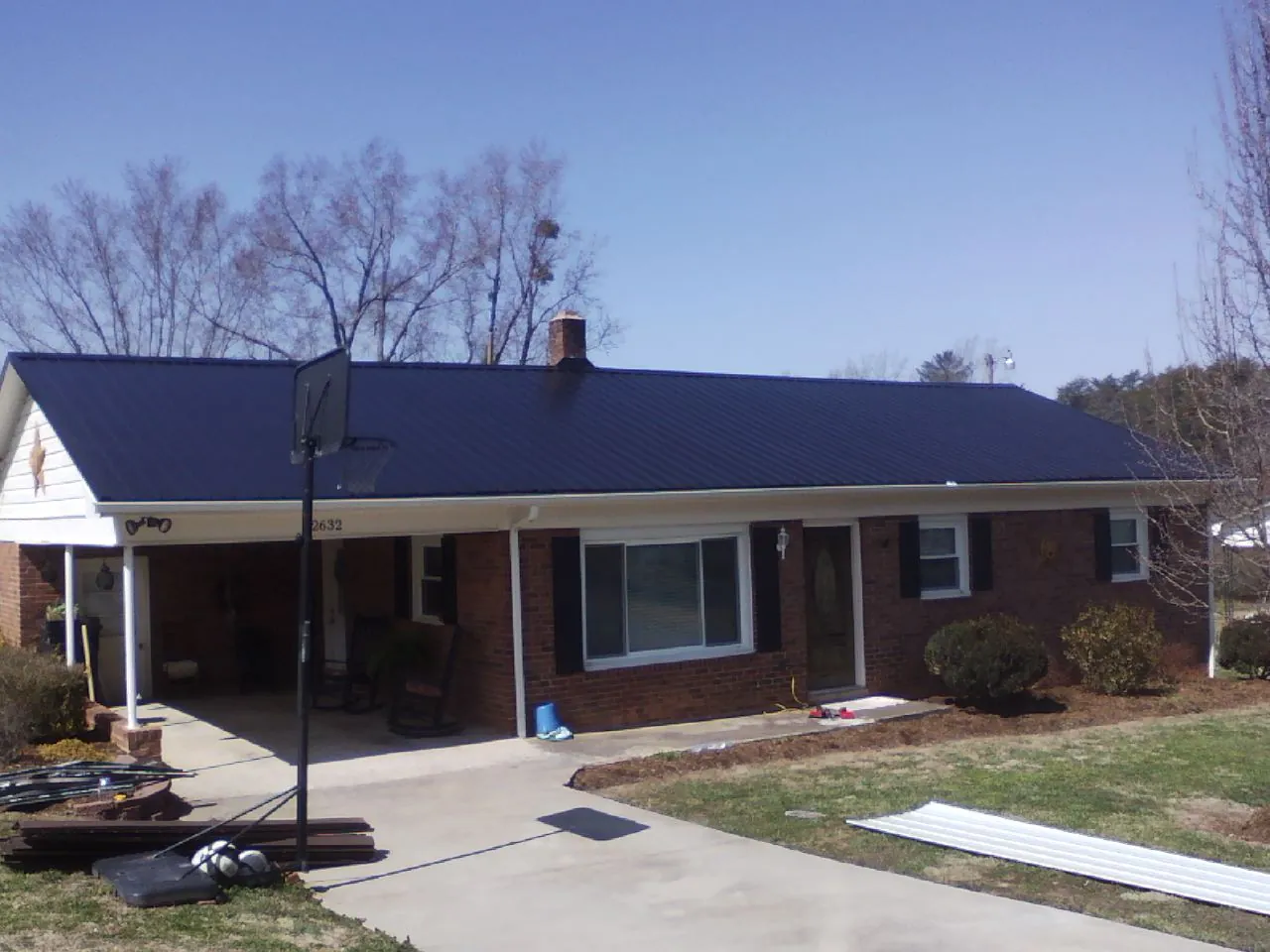 Finished dark blue metal roof on a brick ranch with a carport in Wentworth