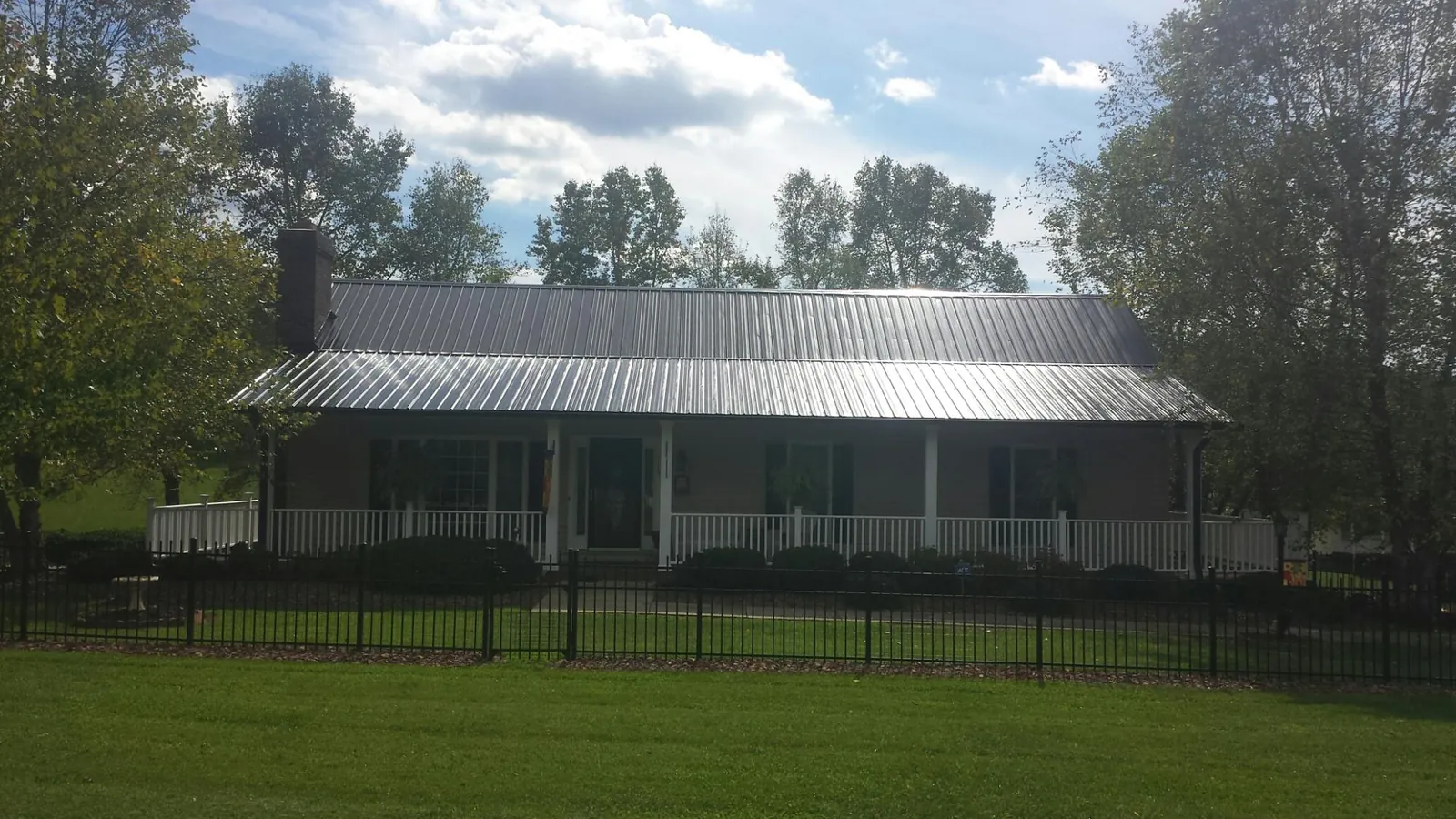 Gray metal roof on a brick ranch with a full width front porch — Gutter Guard Installation work by our crew in Wentworth