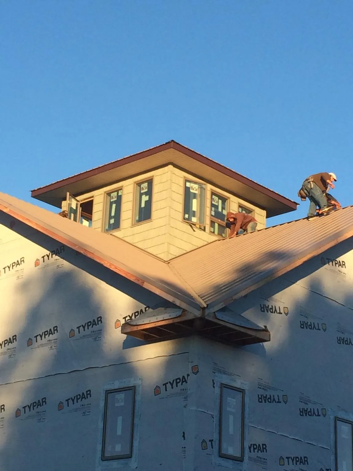 Roofers working around a rooftop cupola on a new metal roof at sunset — Roof Waterproofing in Wentworth by Roofing Brothers